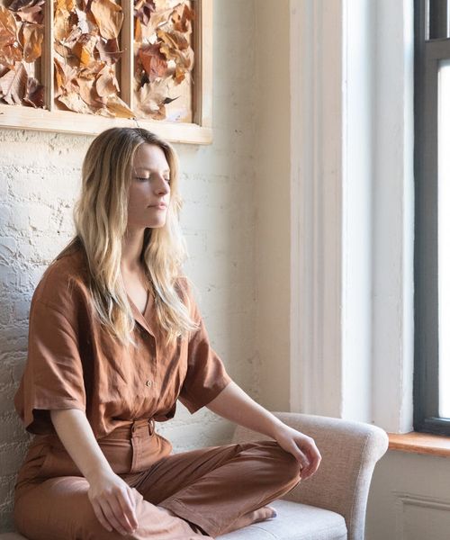 Woman sitting in a calm cross-legged pose with closed eyes.